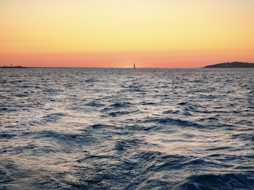Sunrise with a yacht silhouetted in front, looking east up the Needles Channel, delights of early morning sailing