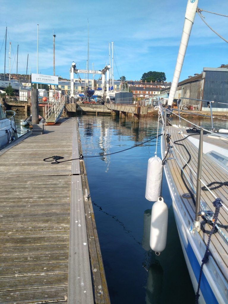WeatherWitch tied up alongside the waiting pontoon for Medina Yard lift berth. Blue skies and still water